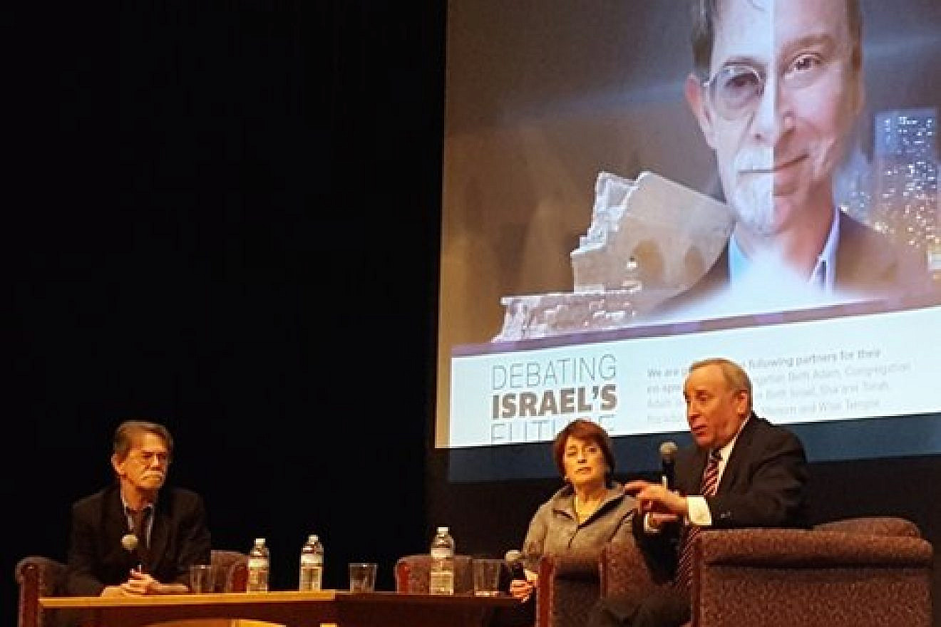 J.J. Goldberg (left) and Jonathan Tobin (right) during one of their debates, in Cincinnati, with a split-screen graphic of their faces on the projector in the background. Credit: Courtesy of J.J. Goldberg/Jonathan Tobin debate tour.