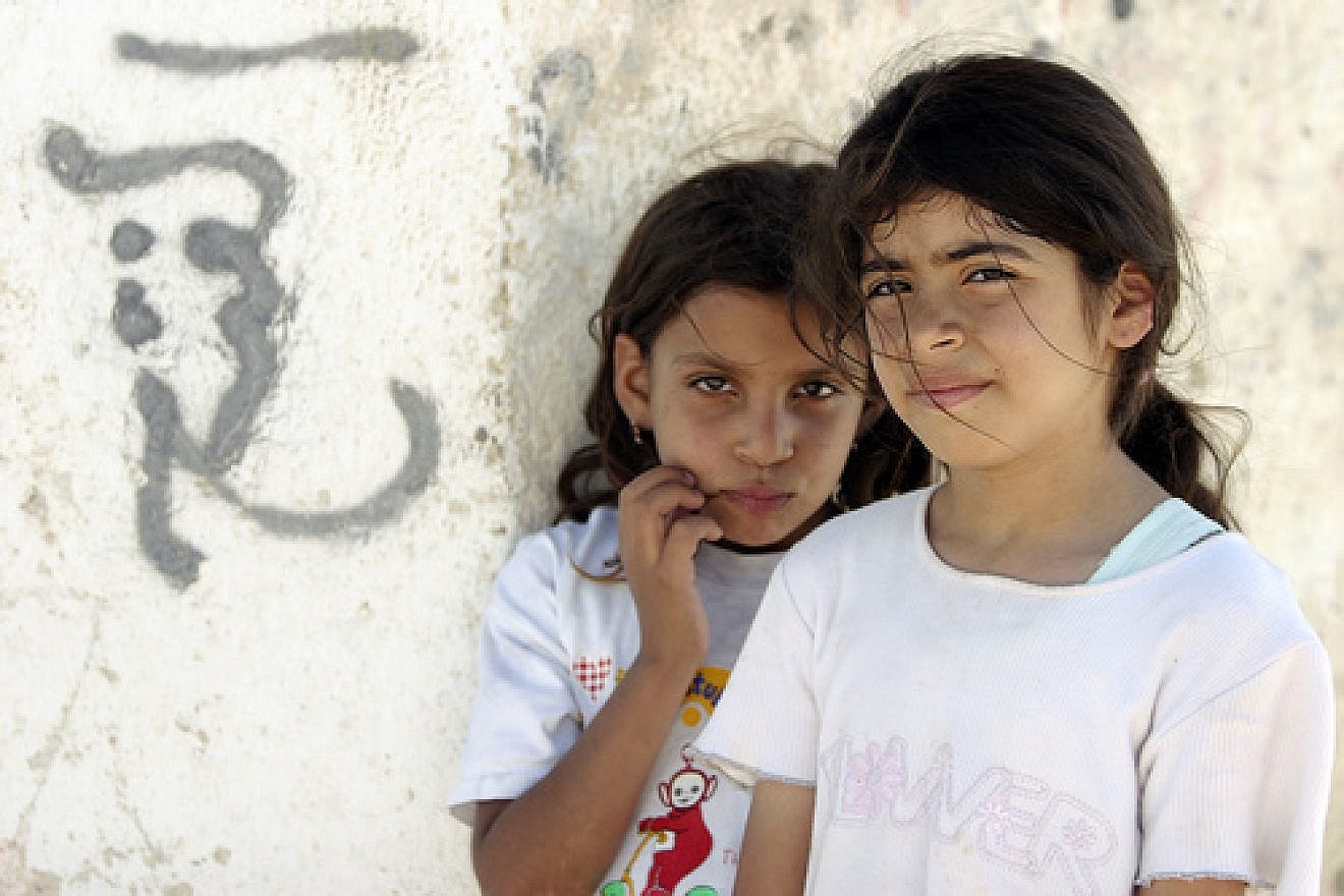 Posing next to graffiti are two young residents of Aqabat Jaber, a United Nations Relief and Works Agency for Palestine Refugees in the Near East (UNRWA) camp for Palestinian refugees located near Jericho. Credit: UN Photo/Stephenie Hollyman.