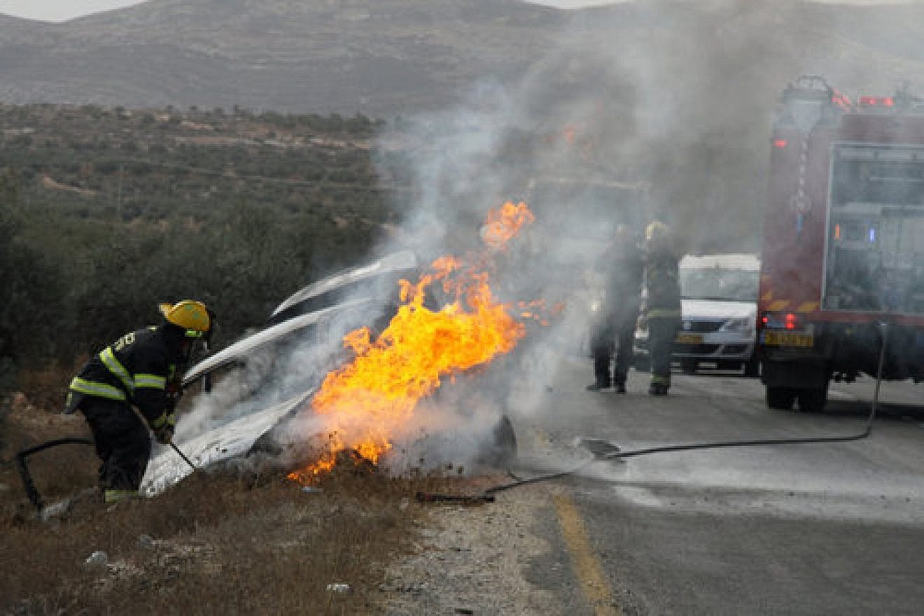 Firefighters put out a blaze from a burning car belonging to Israeli Jews near the West Bank village of Tuqua on Nov. 8, 2013. In the attack, an Israeli woman sustained light-to-moderate wounds, and one of her children was lightly injured, after a firebomb was hurled at their vehicle near Tekoa in Gush Etzion. Credit: Gershon Elinson/Flash90.