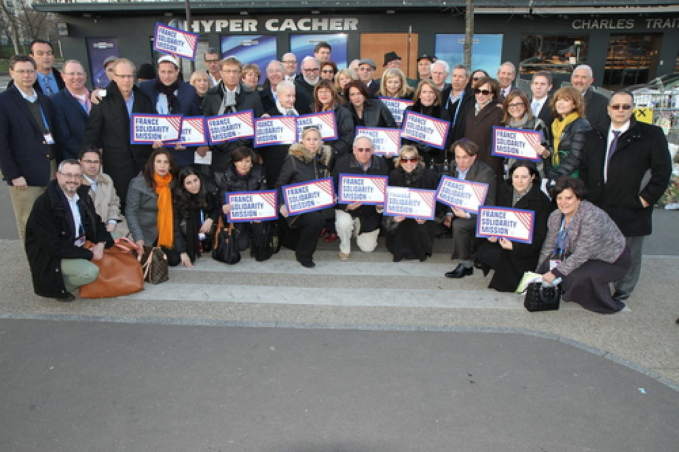 Participants of the Jewish Federations of North America mission to Paris pose in front of the Hyper Cacher kosher grocery in February 2015, where four Jewish shoppers were killed weeks before in an Islamist terror attack. Credit: The Jewish Federations of North America.