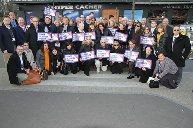 Participants of the Jewish Federations of North America mission to Paris pose in front of the Hyper Cacher kosher grocery in February 2015, where four Jewish shoppers were killed weeks before in an Islamist terror attack. Credit: The Jewish Federations of North America.