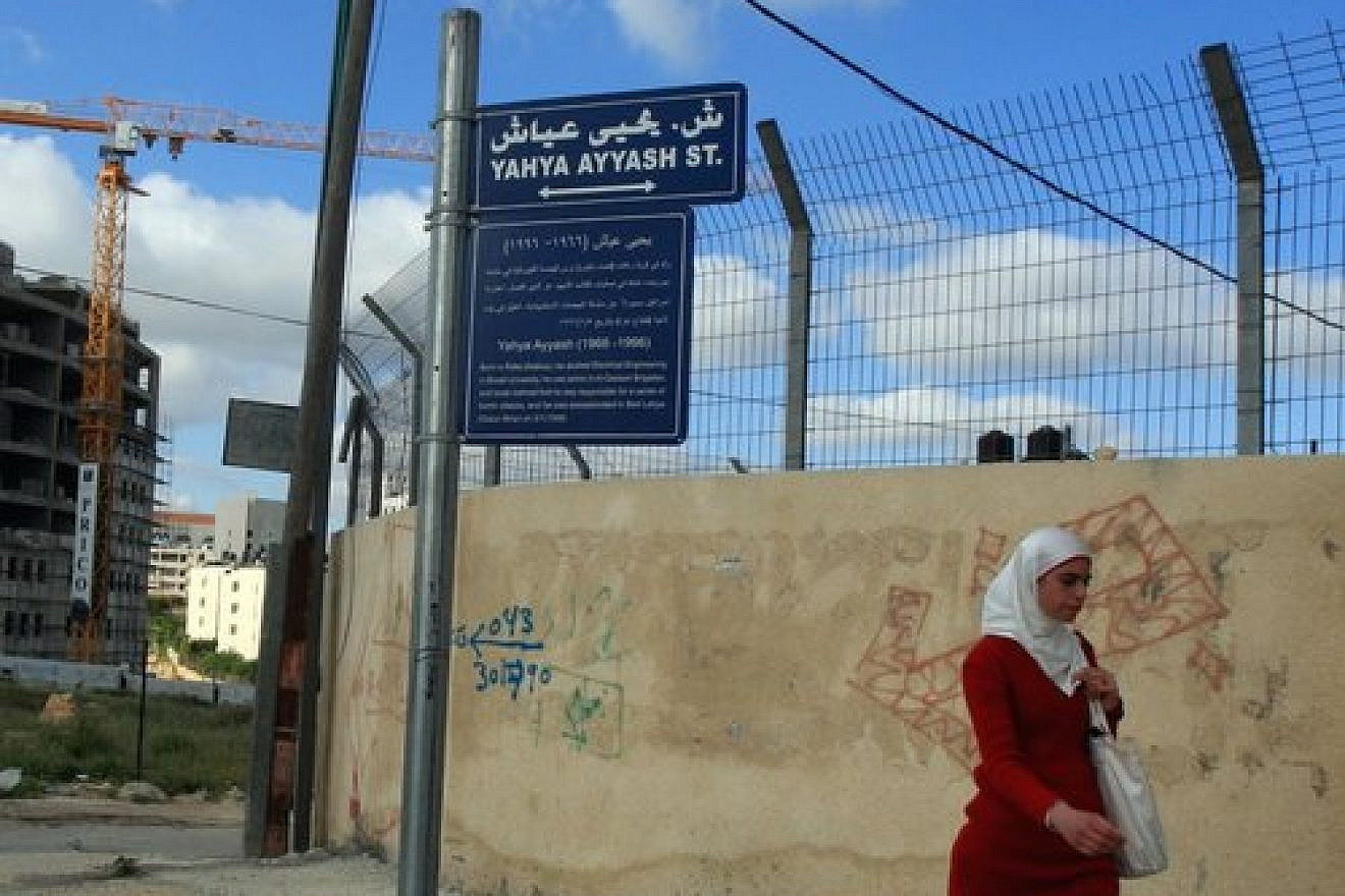 In the de facto Palestinian Authority capital of Ramallah in the West Bank, a Palestinian woman walks past a street sign bearing the name of Yahya Ayyash, the Hamas terror group’s former chief bomb-maker. Credit: Issam Rimawi/Flash90.