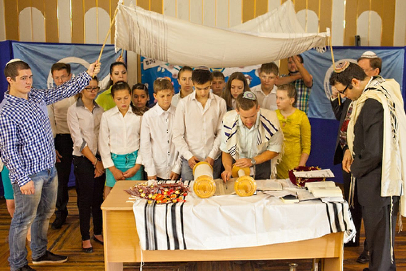 Participants in the Bar/Bat Mitzvah Family Camp reading from a Torah scroll in the Siberian city of Novosibirsk in August 2014. Credit: Roman Ibragimov.