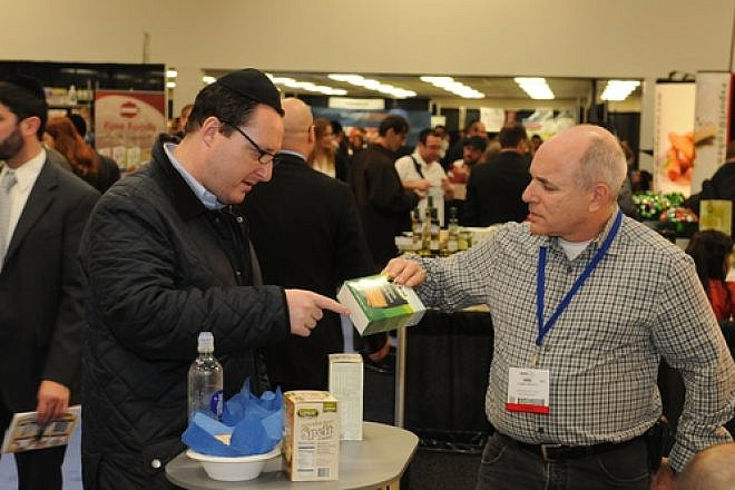 A Kosherfest 2013 vendor speaks with an attendee about Aviva Organic Petit Beurre Biscuits, which Aviva Organic describes as "delicious healthy cookies made of whole wheat flour, a great healthy treat for children & adult." On the table are whole grain spelt crackers from Landau Kosher. Credit: Kosherfest.