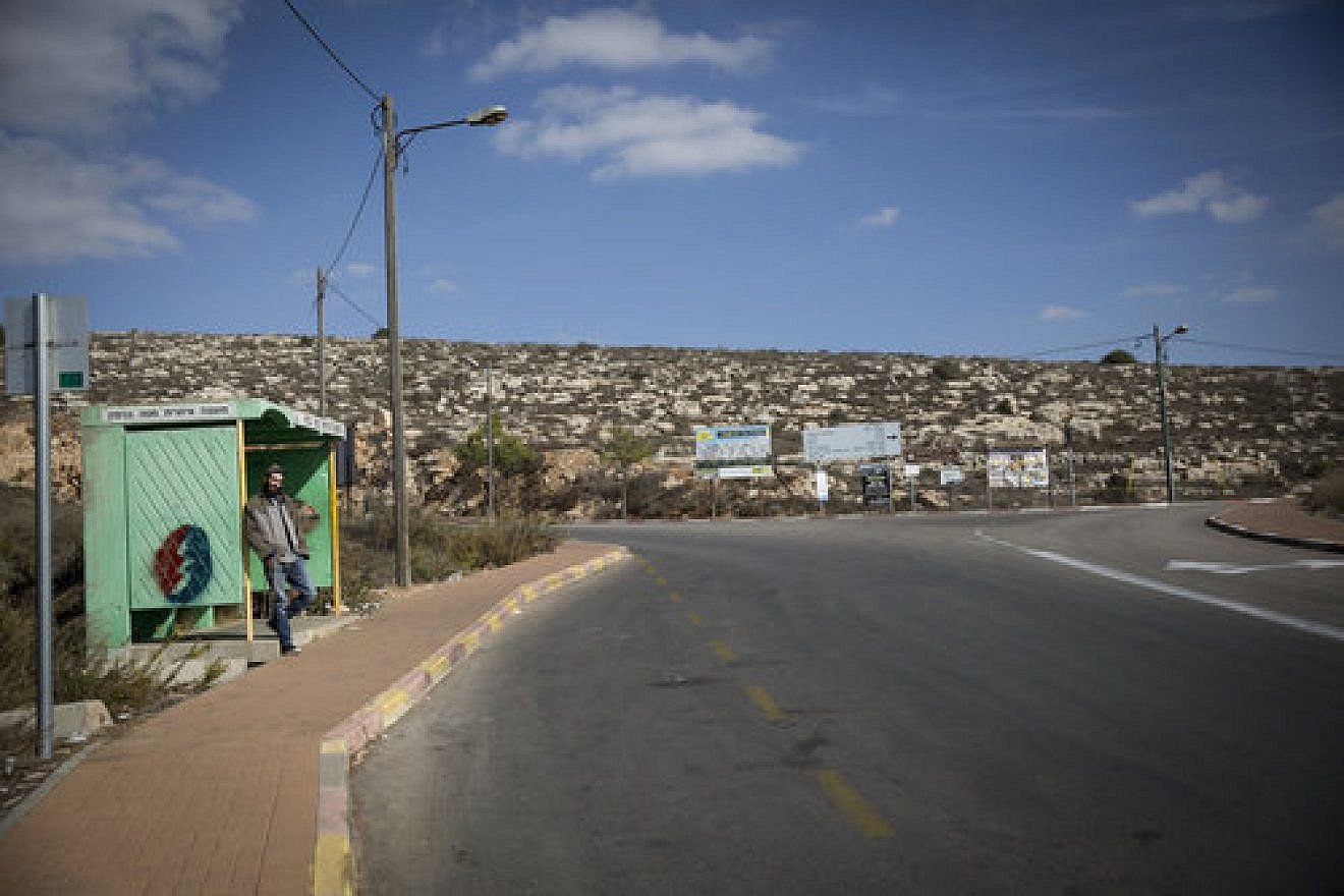 A Jewish man waits at a bus stop near the Israeli settlement of Shiloh, Nov. 17, 2016. The Israeli army evacuated Malachei Hashalom, an unauthorized encampment near Shiloh. Credit: Miriam Alster/Flash90.