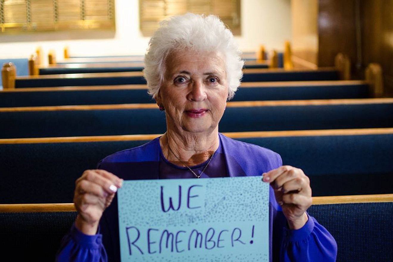 A woman holds a “We Remember” sign as part of the the World Jewish Congress's social media campaign. Credit: Facebook.