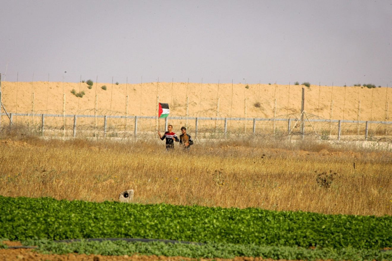 Palestinians wave a flag near the border fence east of Kahn Yunis in the southern Gaza Strip, on May 19, 2017. Credit: Abed Rahim Khatib/ Flash90.