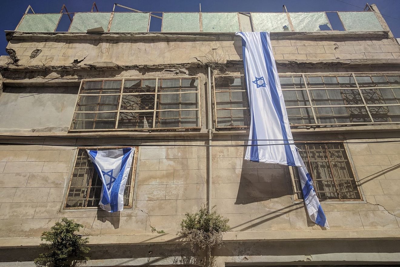 Israeli flags hang on the new Beit Rachel and Beit Leah buildings in Hebron. Photo by Yishai Fleisher