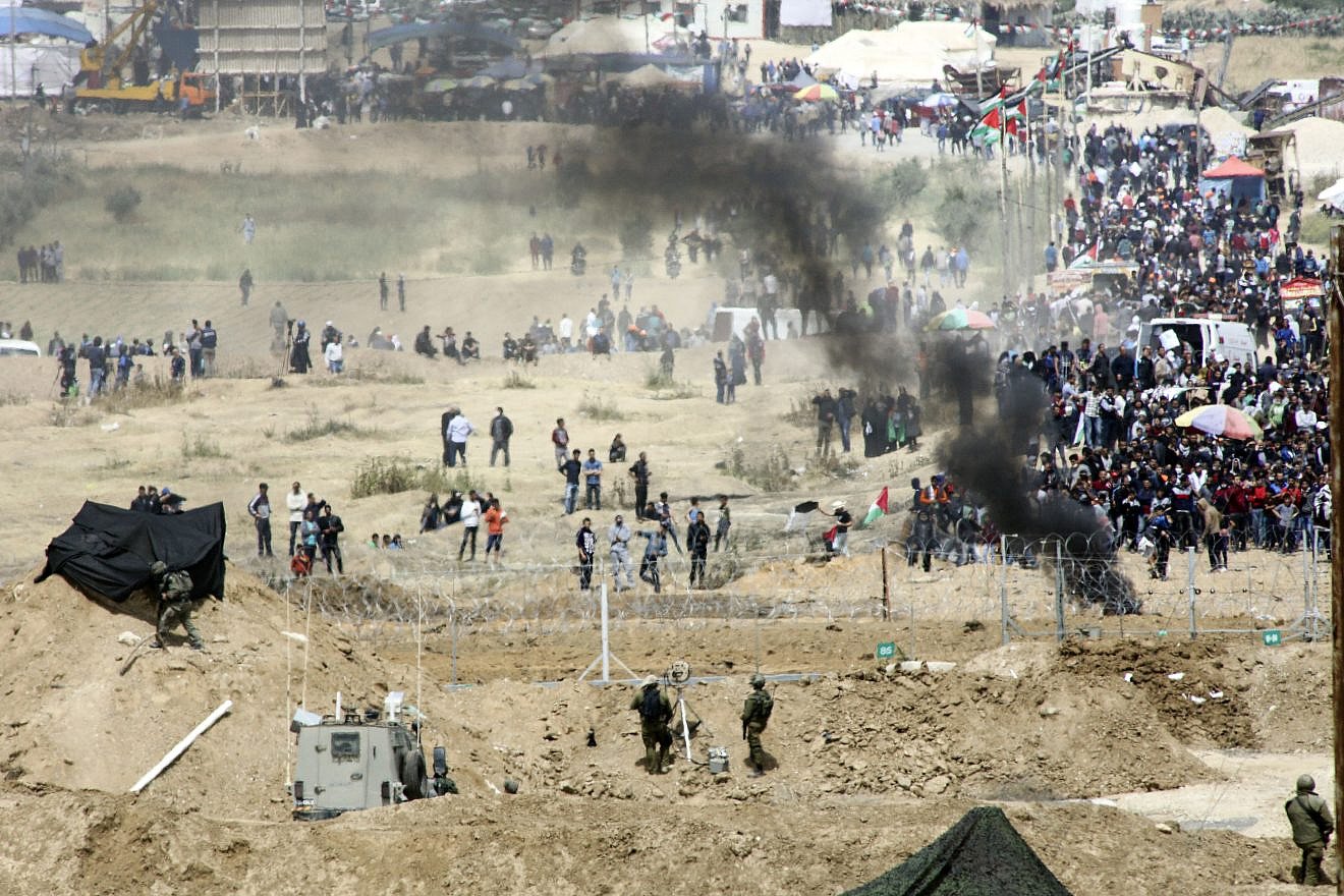 Palestinian protesters demonstrate and burn tires near the border with Israel in the Gaza Strip, as seen from the Israeli side of the border, on April 13, 2018. Credit: Sliman Khader/Flash90