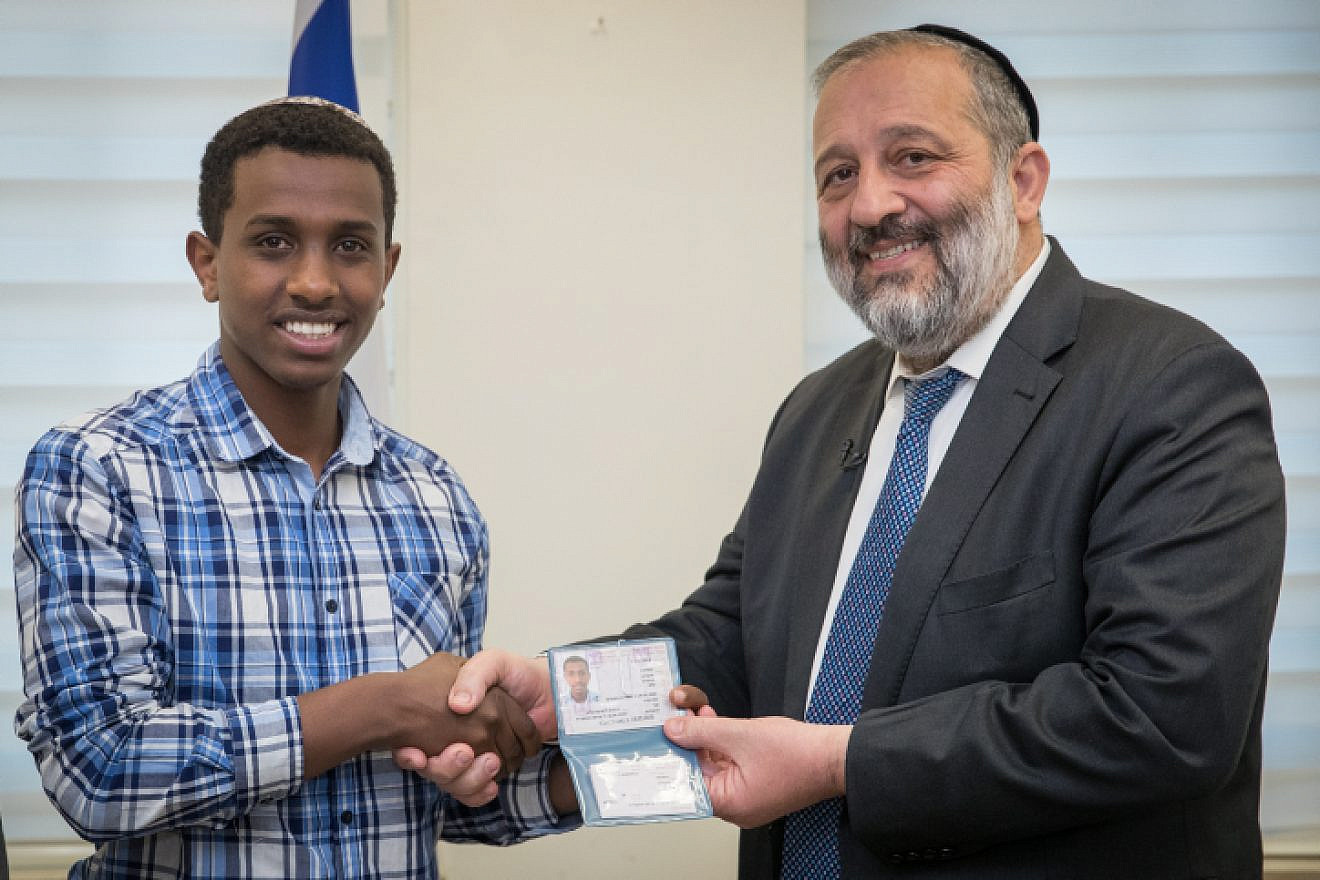 Sintayehu Shaparau from Ethiopia, who is competing in the annual International Bible Quiz in Israel, is handed a national ID form by Israel Minister of Interior Affairs Aryeh Deri during a ceremony at the Interior ministry office in Jerusalem on April 16, 2018. Photo by Yonatan Sindel/Flash90