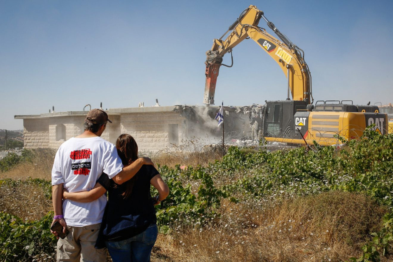 A couple views a tractor demolishing a home in the illegal Jewish neighborhood of Netiv Ha’avot in Gush Etzion, two days after residents were evicted, June 14, 2018. Photo by Gershon Elinson/Flash90.