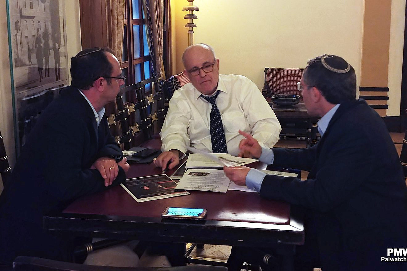 Palestinian Media Watch director Itamar Marcus and head of its legal strategies Maurice Hirsch show former New York City Mayor and current attorney Rudy Giuliani their reports on the Palestinian Authority's payment of salaries to terrorist prisoners, 31 P.A. schools named after terrorists and texts presenting terrorists as role models from P.A. schoolbooks. (Credit: PMW)