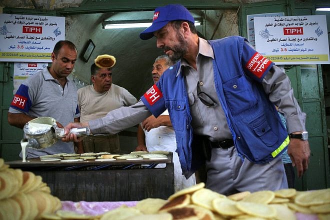 An international observer assists Palestinian shop owners in the old city of Hebron while preparing Ramadan sweets, Aug. 12, 2010. Photo by Najeh Hashlamoun/Flash90.