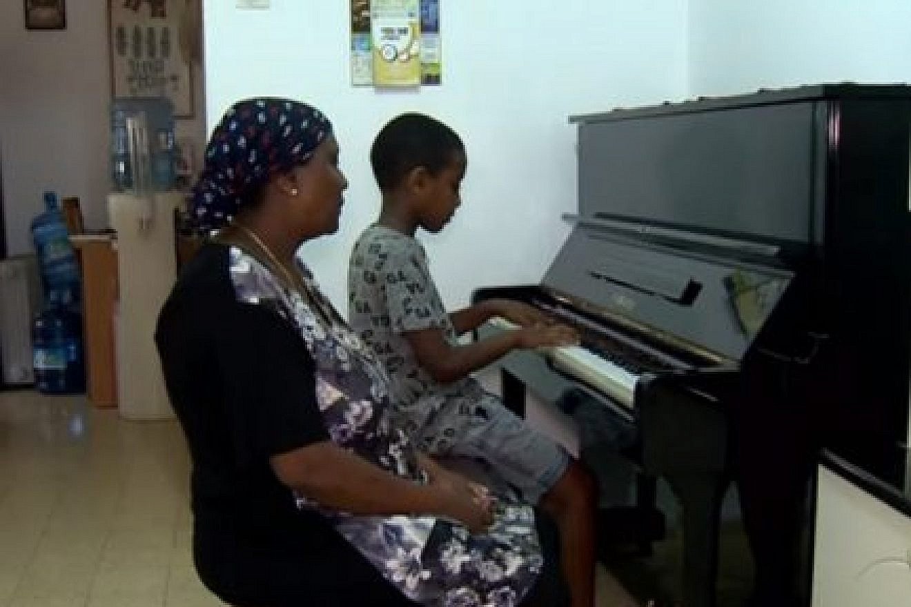Oshri Bitau with his mother and their new piano. Photo: Hadashot news.