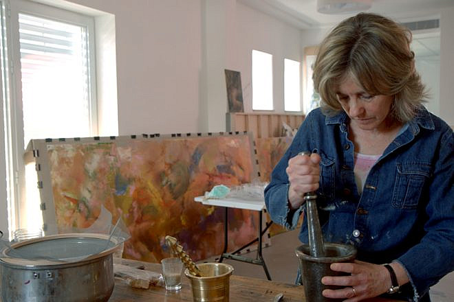Beverly Barkat grinds material into fragments with a pestle and mortar for her artwork “After the Tribes,” to be exhibited in Rome. Credit: Photo by Tor Ben Mayor.