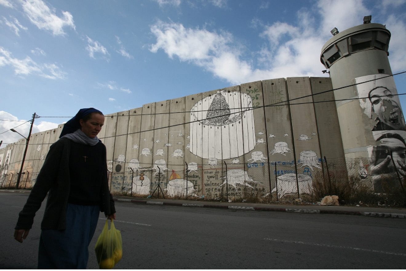 A nun hurries by the Judea and Samaria security barrier toward an IDF checkpoint on her way from Jerusalem to the Church of Nativity in Bethlehem, Dec. 11, 2008. Photo by Yossi Zamir/Flash90.