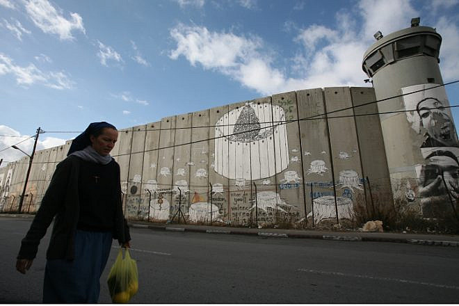 A nun hurries by the Judea and Samaria security barrier toward an IDF checkpoint on her way from Jerusalem to the Church of Nativity in Bethlehem, Dec. 11, 2008. Photo by Yossi Zamir/Flash90.