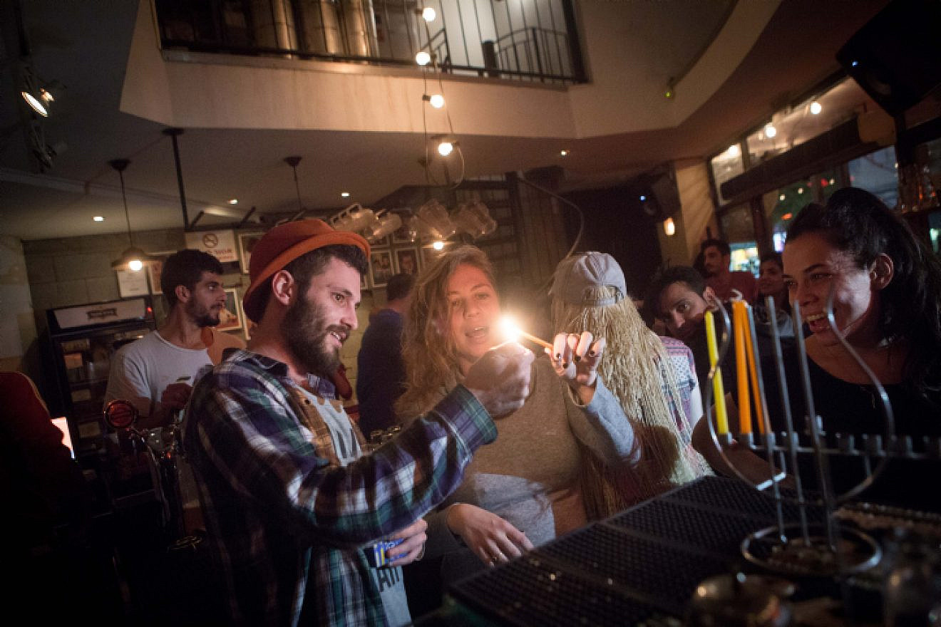Young Israelis light candles for the Jewish holiday of Hanukkah at a bar in Tel Aviv on Dec. 8, 2015.  Photo by Miriam Alster/Flash90.