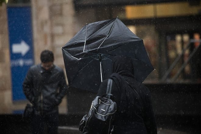 People walk in central Jerusalem on an especially wet day on Dec. 27, 2018. Photo by Yonatan Sindel/Flash90.