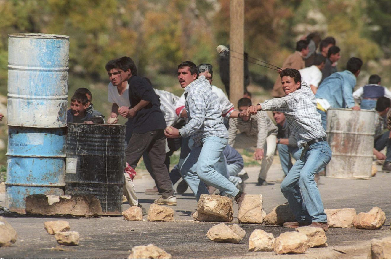 A Palestinian man winds up a slingshot before throwing a rock towards Israeli soldiers in the West bank village of Dura near Hebron, on March 11, 1998. Photo by Nati Shohat/Flash90.