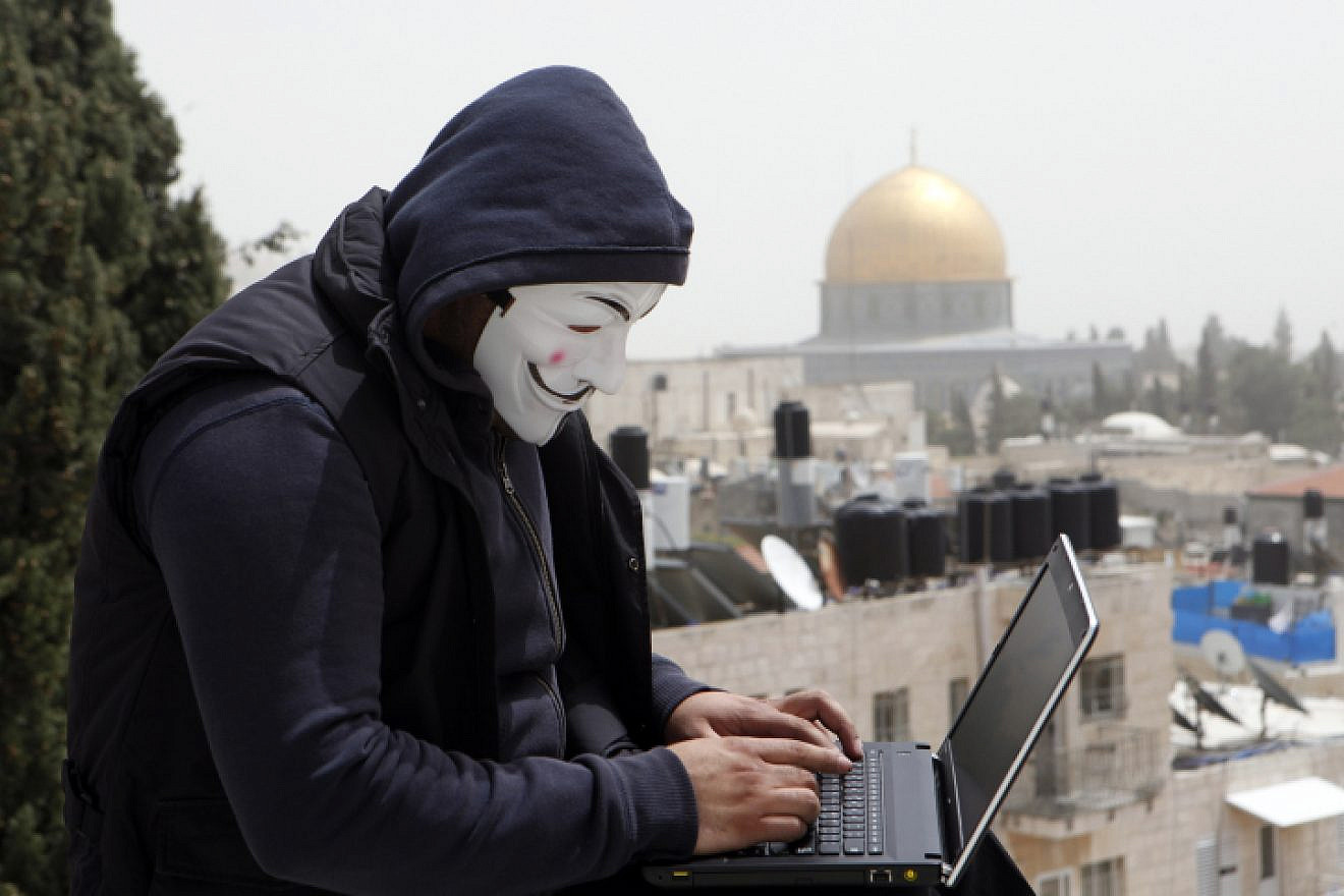 A Palestinian youth wearing masks used by computer hackers who attacked a number of Israeli websites recently, seen backdropped by the Temple Mount in Jerusalem's Old City, April 8, 2013. Photo by Sliman Khader/Flash90.
