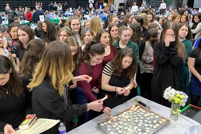 Women light candles before the start of Shabbat at the 25th anniversary dinner of the Shabbat 1800 program at Binghamton University, April 5, 2019. Photo by R. Coschignano/Chabad of Binghamton.