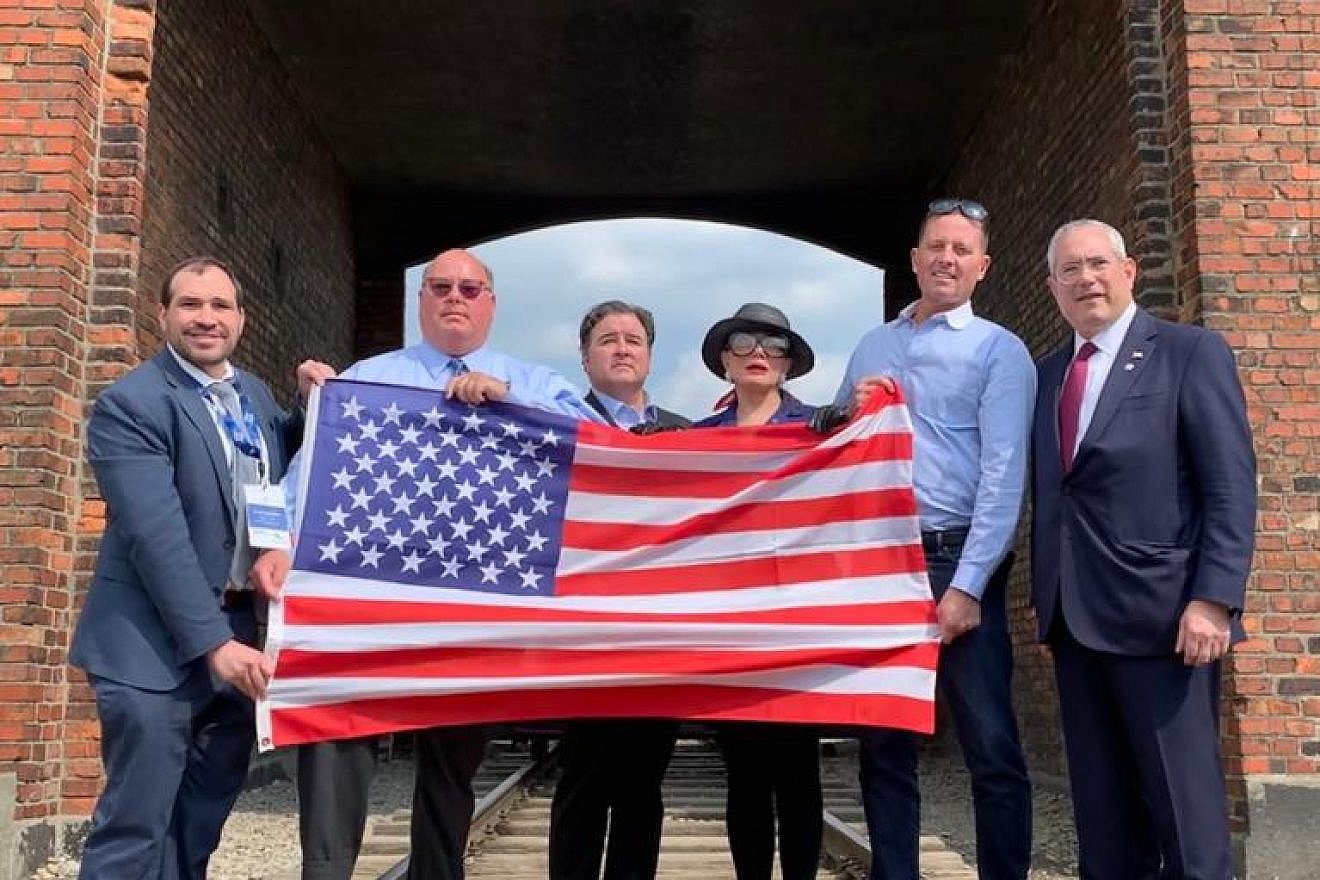 Members of the first-ever official U.S. government delegation to the “March of the Living” hold the American flag up at the Auschwitz-Birkenau concentration camps in Poland on May 2, 2019. Credit: March of the Living.