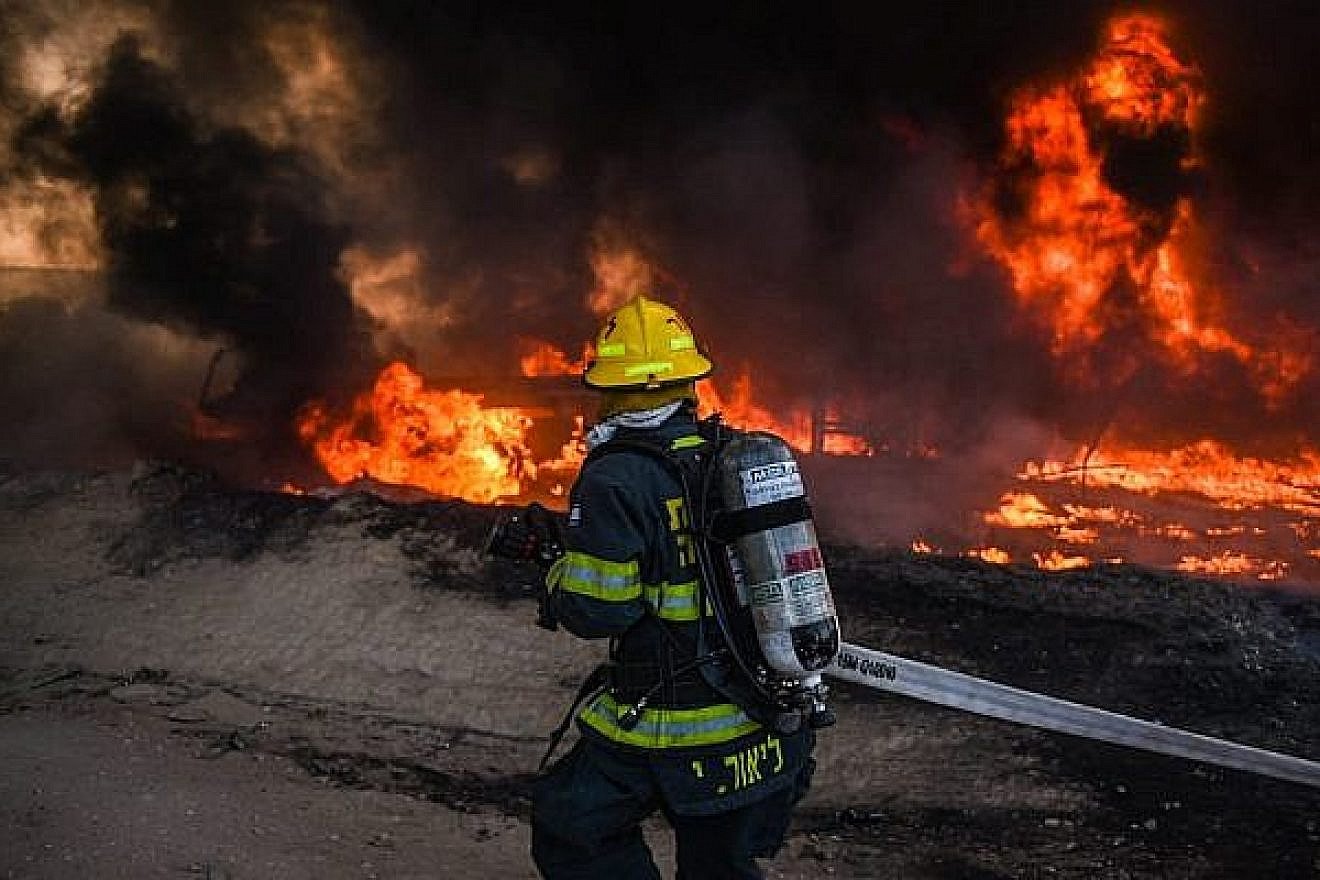 An Israeli firefighter works to extinguish a blaze caused by an incendiary device sent from Gaza into southern Israel on June 27, 2019. Credit: Israel Fire and Rescue Services.