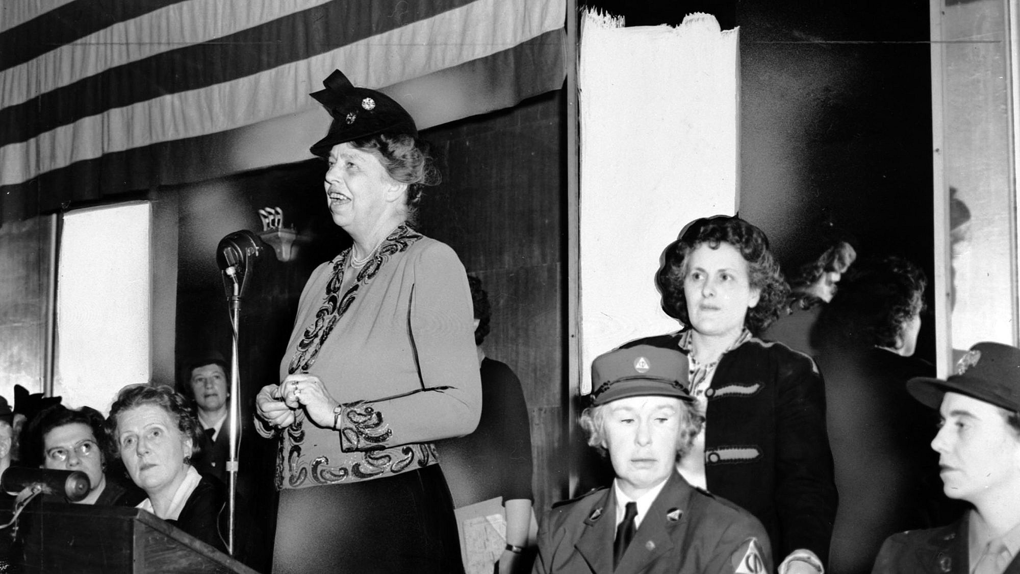 Eleanor Roosevelt speaks to a war-time audience, while Rose Pesotta and others listen. Credit: Flickr.