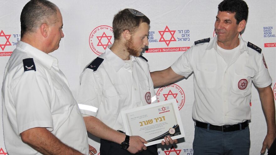 Magen David Adom director general Eli Bin (right) presents Dvir Shnerb with his EMT certificate. Credit: Magen David Adom.