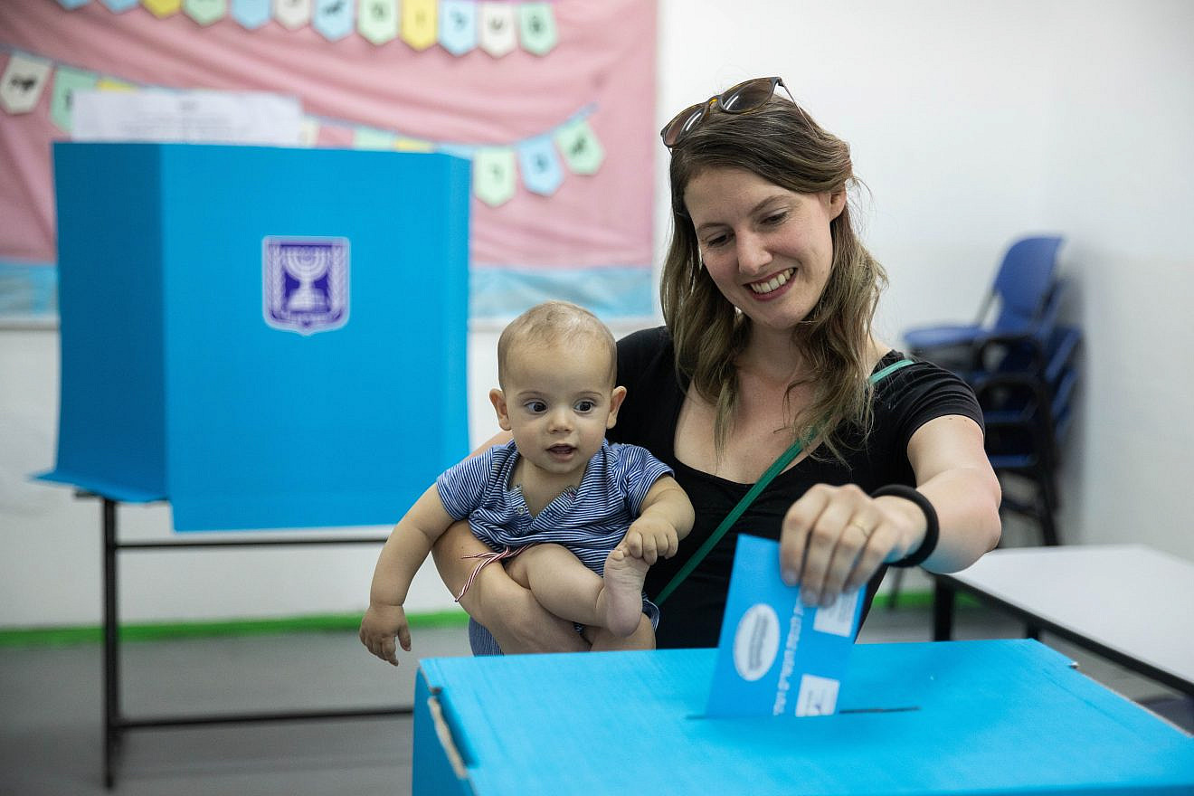 A woman holds her baby as she casts her ballot at a voting station in Jerusalem during the second round of Israeli elections on Sept. 17, 2019. Photo by Yonatan Sindel/Flash90.