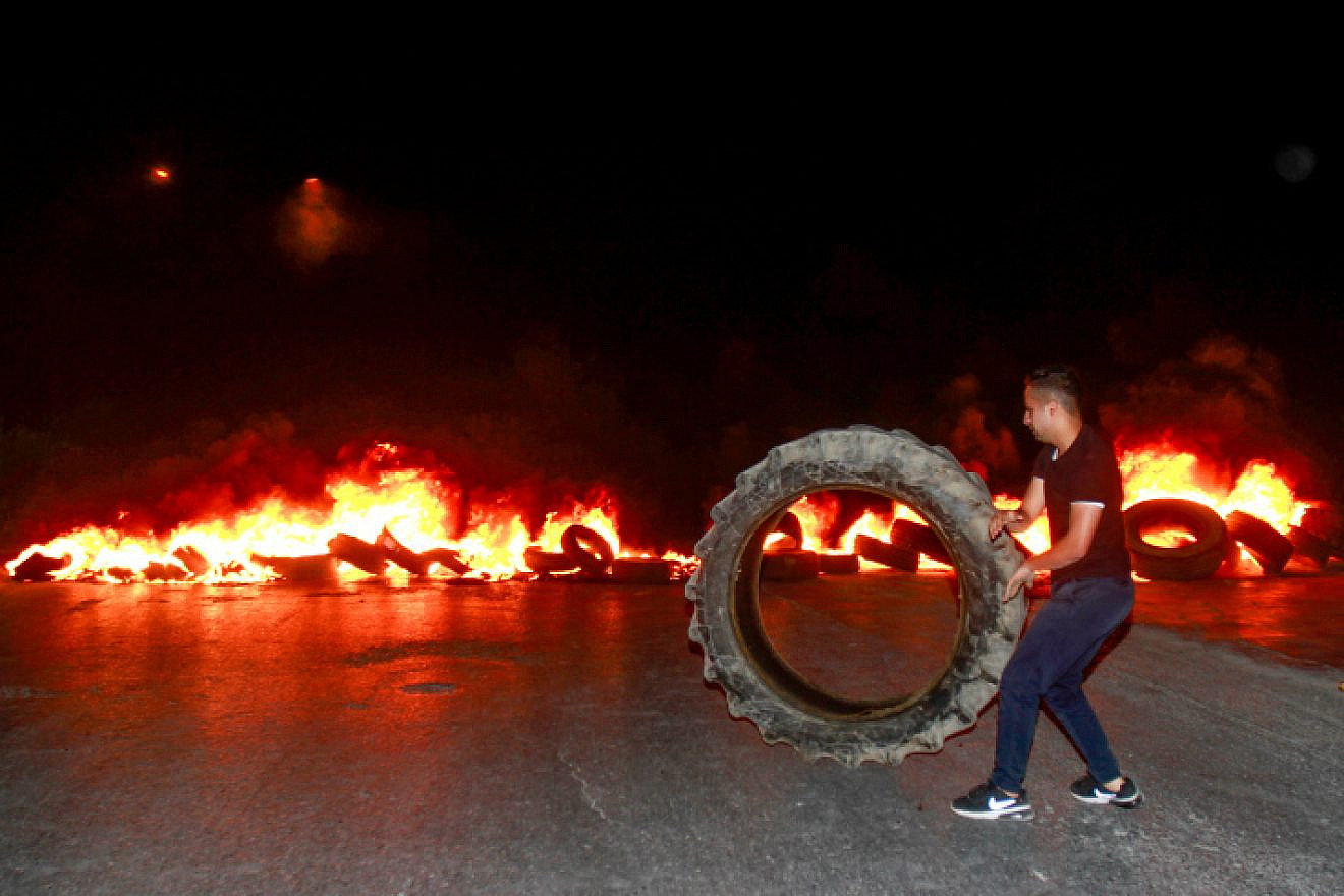 A Palestinian demonstrator burns tires near Joseph's Tomb in the West Bank city of Nablus on July 2, 2019, as thousands of Jews make their way to visit the grave. Photo by Nasser Ishtayeh/Flash90.