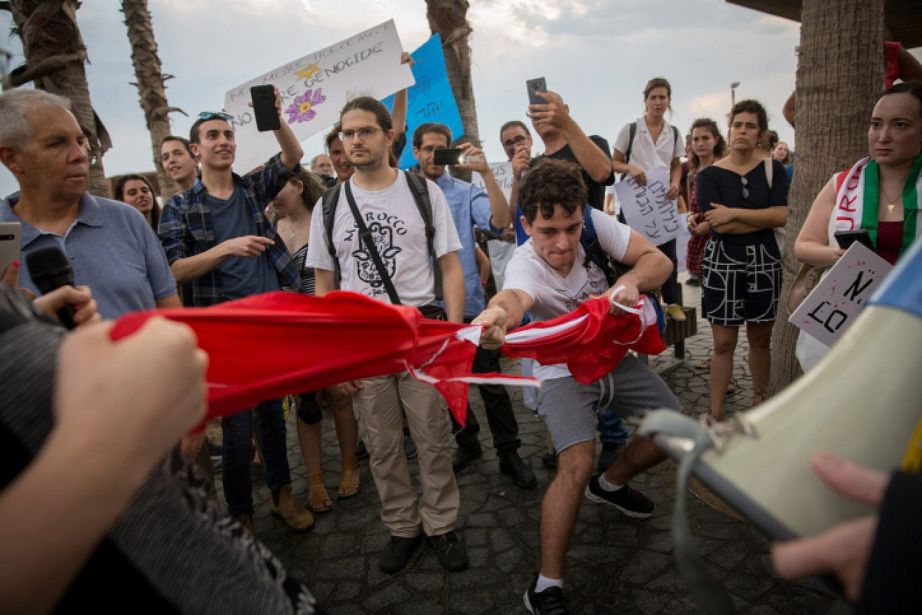 Israeli demonstrators tear a Turkish flag during protest march from the Turkish embassy to the U.S. embassy branch in Tel Aviv in support of the Syrian Kurds and against Turkey's incursion into Syria, Oct. 15, 2019. Photo by Miriam Alster/Flash90.