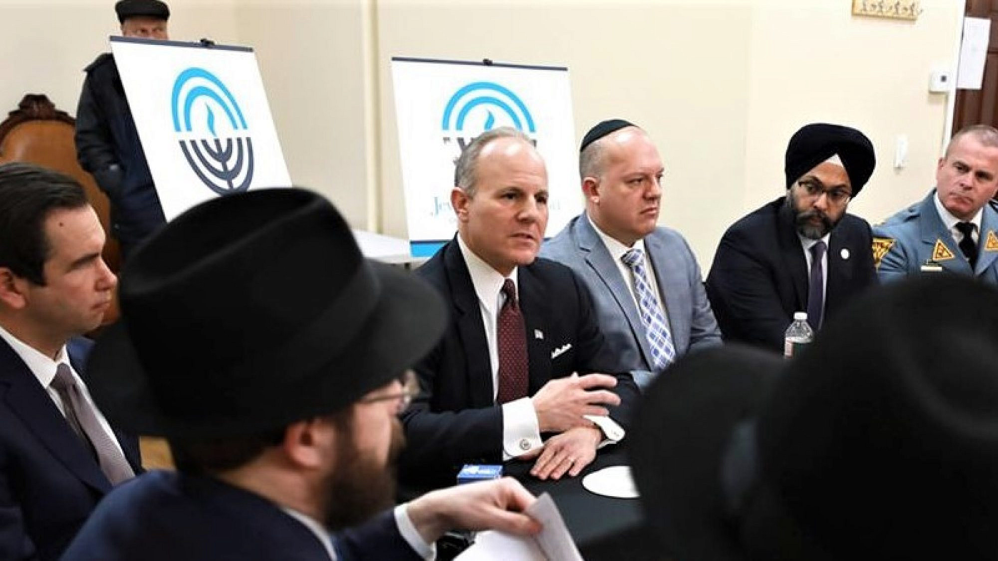 Among those who joined a community forum in Jersey City were, from left, Rabbi Moshe Schapiro, co-director of Chabad of Hoboken and Jersey City; Jersey City Mayor Steven Fulop; Elan Carr, the Trump administration’s Special Envoy for Monitoring and Combating Anti-Semitism; Jason Shames, CEO and executive vice president of the Jewish Federation of Northern New Jersey; New Jersey Attorney General Gurbir Grewal; and New Jersey State Police Superintendent Col. Patrick Callahan. (Photo: New Jersey OAG)