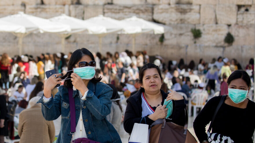 Tourists wear face masks for fear of the coronavirus while touring the Western Wall in the Old City of Jerusalem on March 5, 2020. Photo by Olivier Fitoussi/Flash90.