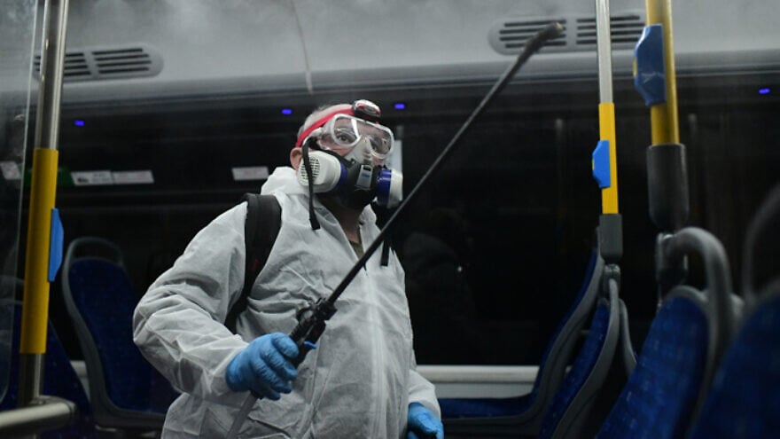 Workers wearing protective suits disinfect a bus in Tel Aviv as a preventive measure amid fears over the spread of coronavirus, March 9, 2020. Photo by Tomer Neuberg/Flash90.
