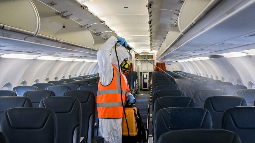 A worker wearing protective clothing disinfects a plane after its arrival from Moscow at the Ben-Gurion International Airport as part of measures to prevent the spread of the coronavirus, May 5, 2020. Photo by Yossi Zeliger/Flash90.