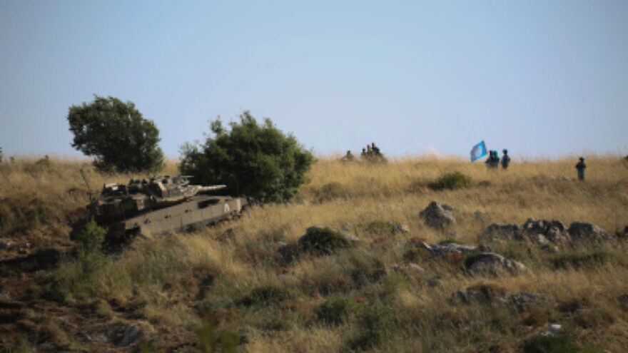 An Israeli Merkava tank takes part in routine maneuvers near the "blue line" drawn by the U.N. to mark Israel's withdrawal from southern Lebanon in 2000, as Lebanese soldiers watch from the Lebanese village of Adaisseh. June 03, 2020. Photo by David Cohen/Flash90.