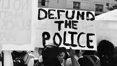 A demonstrator at a George Floyd protest holds up a "Defund the Police" sign on June 5, 2020. Photo: Taymaz Valley via Wikimedia Commons.