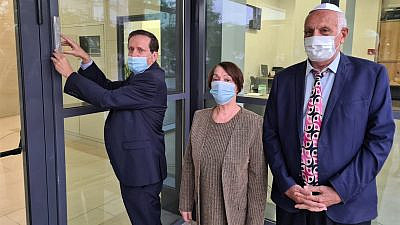 Residents of the Joseph Wilf Senior Citizens House in Tel Aviv with Isaac Herzog (left), chairman of the Jewish Agency, who hangs a mezuzah on the entrance door on Dec. 15, 2020. Credit: Amigour/The Jewish Agency for Israel.