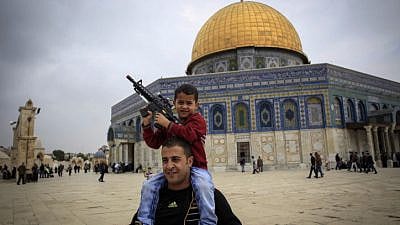 A Palestinian child plays with a toy gun on his father's shoulders at the Al-Aqsa mosque compound in Jerusalem's Old City on Nov. 6, 2015. Photo by Muammar Awad/Flash90.