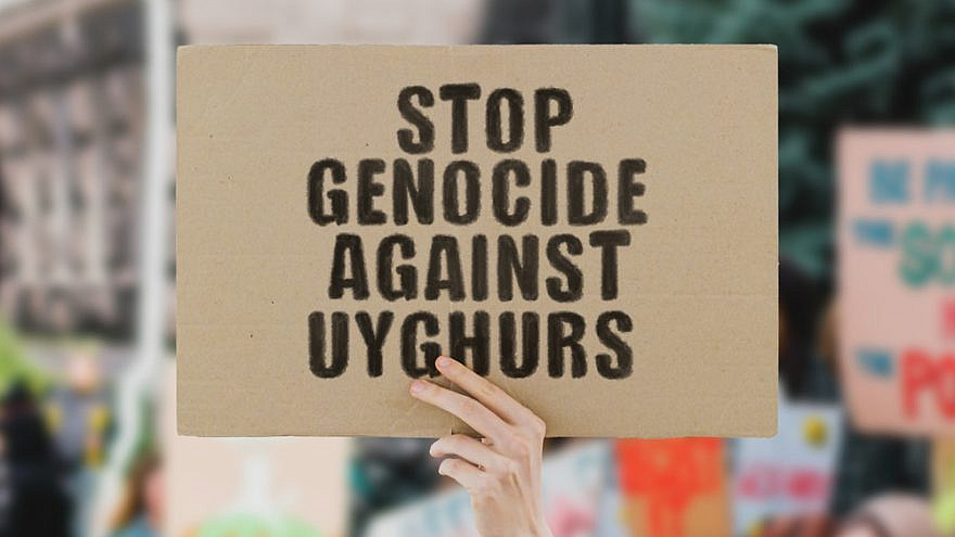 A man holds up a sign protesting the genocide against Uyghur Muslims by the Chinese government. Credit: AndriiKoval/Shutterstock.