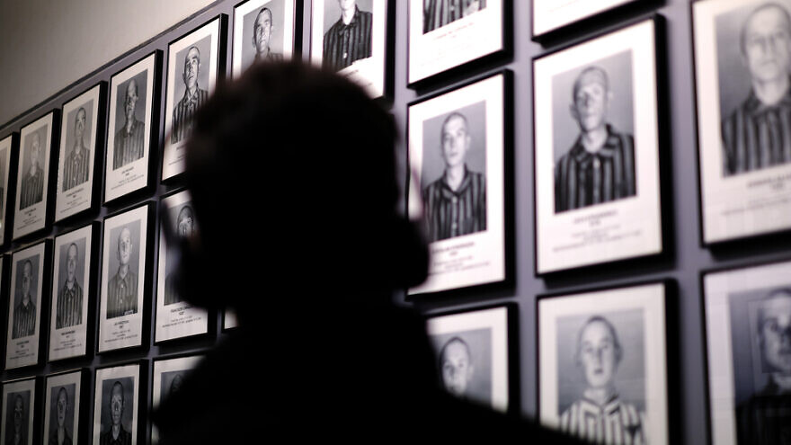 A visitor looks at photographs of camp inmates at the Auschwitz-Birkenau Museum and Memorial in Oswiecim, Poland. Credit: Desi H. Sitorus/Shutterstock.