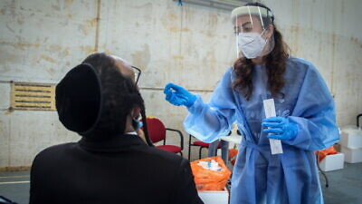 An Israeli health worker takes COVID-19 test samples in Tzfat on Aug. 31, 2021. Photo by David Cohen/Flash90.