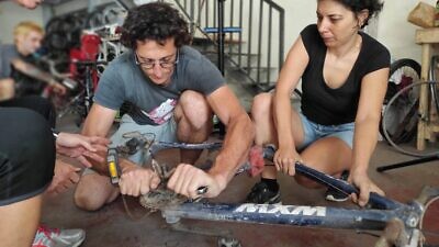 Nathanael Singer showing workshop visitors how to fix a bicycle. Photo courtesy of Pnimeet.