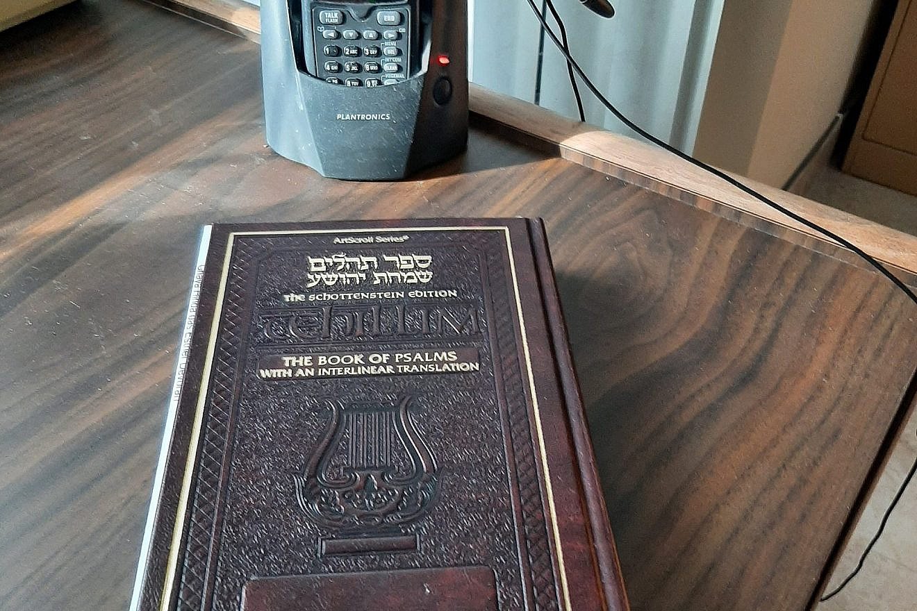Flora Goldsmith’s setup for the OU tehillim and chizzuk calls includes a siddur and a headset