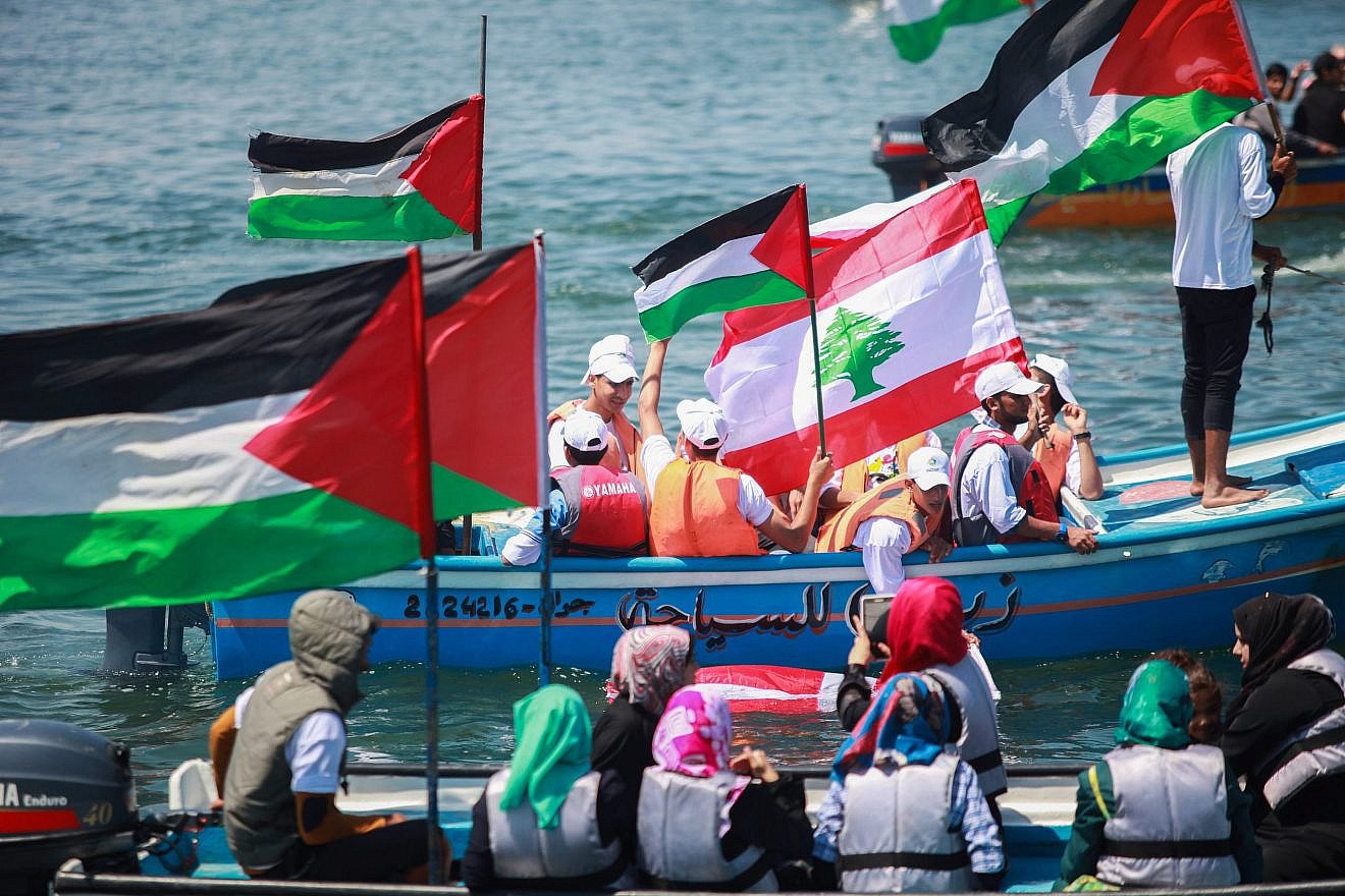 Palestinians hold flags as they ride a boat during a rally marking the fifth anniversary of the "Mavi Marmara" flotilla at the seaport of Gaza City on May 31, 2015. Credit: Aaed Tayeh/Flash90.