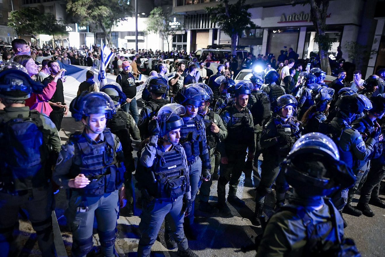 Police officers stand guard while Israelis demonstrate against Prime Minister Benjamin Netanyahu's wife Sara Netanyahu, outside a hair salon in Tel Aviv on March 1, 2023. Photo: Avshalom Sassoni/Flash90