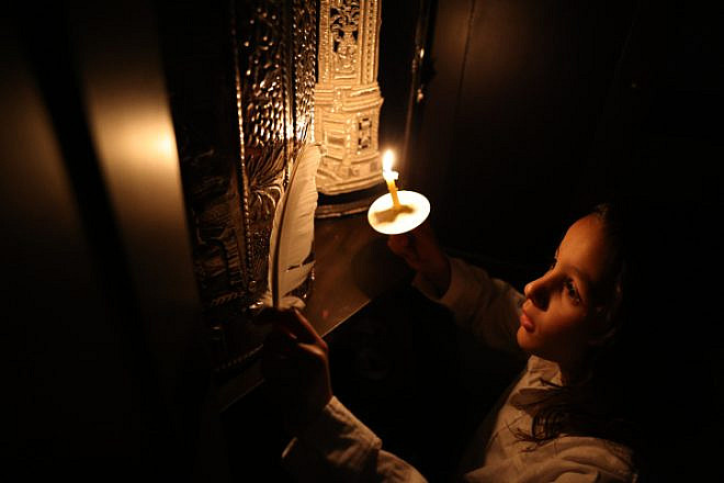 Sahar Amsalem and his son Shimon perform search for remains of leaven after cleaning their home, in Tzfat on the night before Passover, on April 4, 2023. Photo by David Cohen/Flash90.