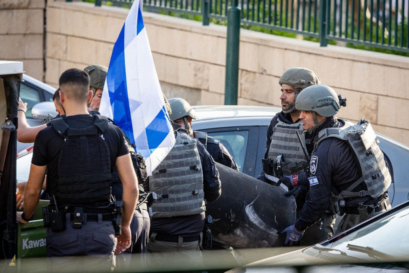 Police dispose of a rocket fragment that damaged a parking lot in Netivot in southern Israel, on May 13, 2023. Photo by Yonatan Sindel/Flash90.